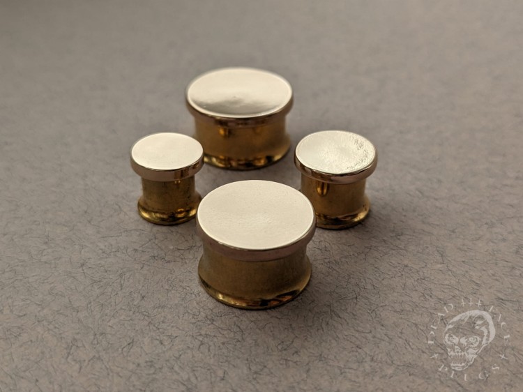 Mirror finished bronze disc plugs looking like solid gold gauges on stainless steel tunnels