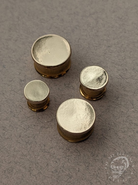 Mirror finished bronze disc plugs looking like solid gold gauges on stainless steel tunnels