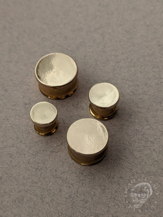 Mirror finished bronze disc plugs looking like solid gold gauges on stainless steel tunnels