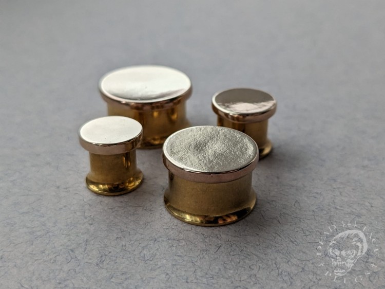 Mirror finished bronze disc plugs looking like solid gold gauges on stainless steel tunnels