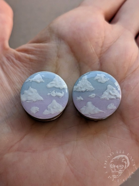 Silver ear plugs with blue and lilac violet purple ombre effect, decorated with fluffy white clouds.