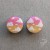Silver ear plugs with pink and yellow ombre effect, decorated with fluffy white clouds.