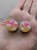 Silver ear plugs with pink and yellow ombre effect, decorated with fluffy white clouds.